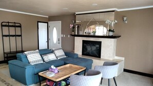 A living room with a blue sofa, a wooden coffee table, and two white chairs. - House with Panoramic view 15 mins to SF airport (Daly City)
