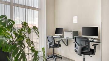 A modern office space with two desks, each with a computer monitor, office chairs, and a printer.