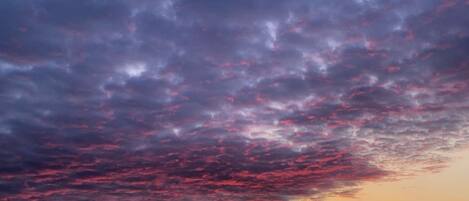 A sunset over a body of water with a cloudy sky.