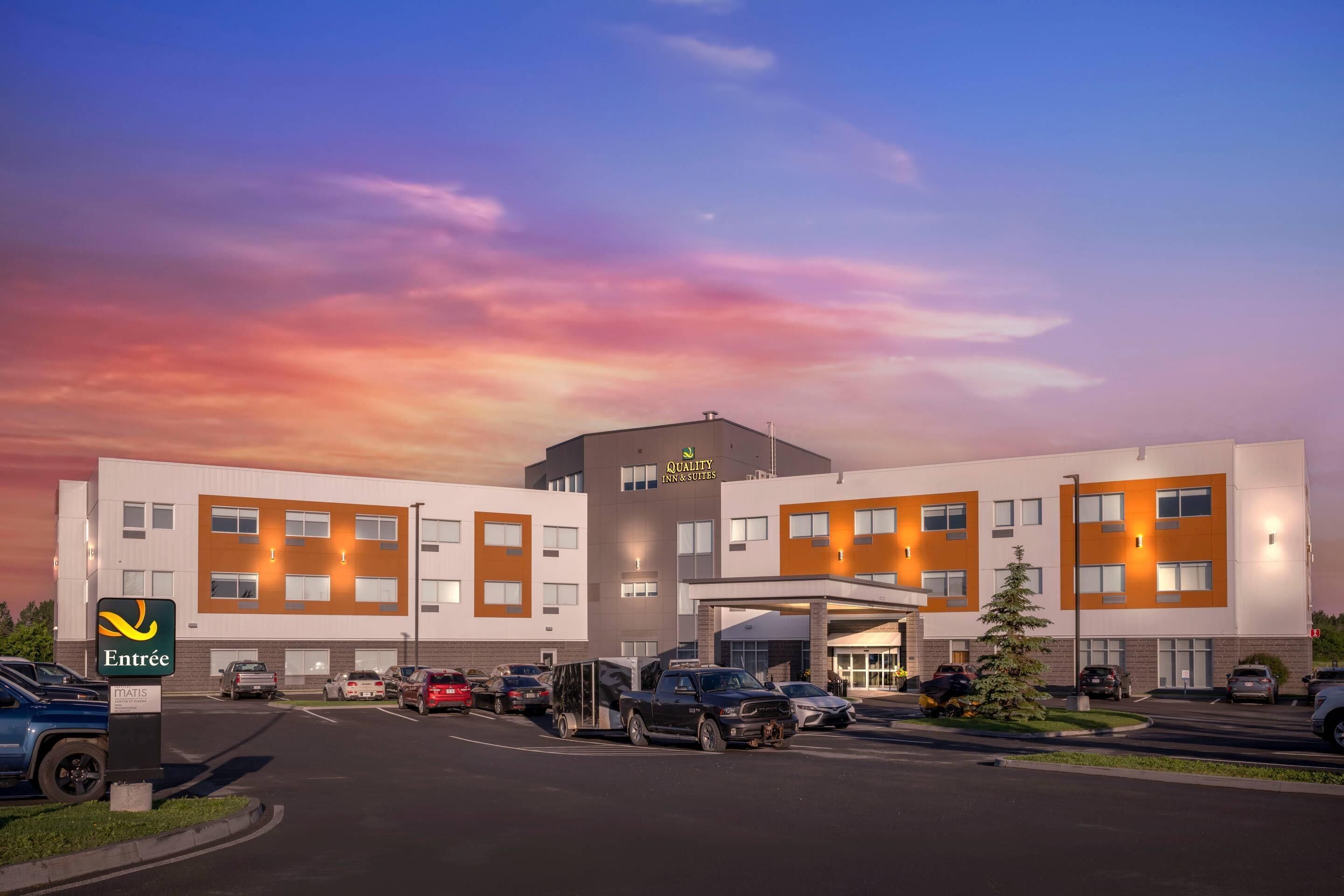 A hotel with a modern design, featuring a central entrance and multiple parking spaces.