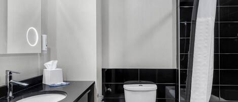 A modern bathroom with a black countertop sink, a white toilet, and a shower curtain.