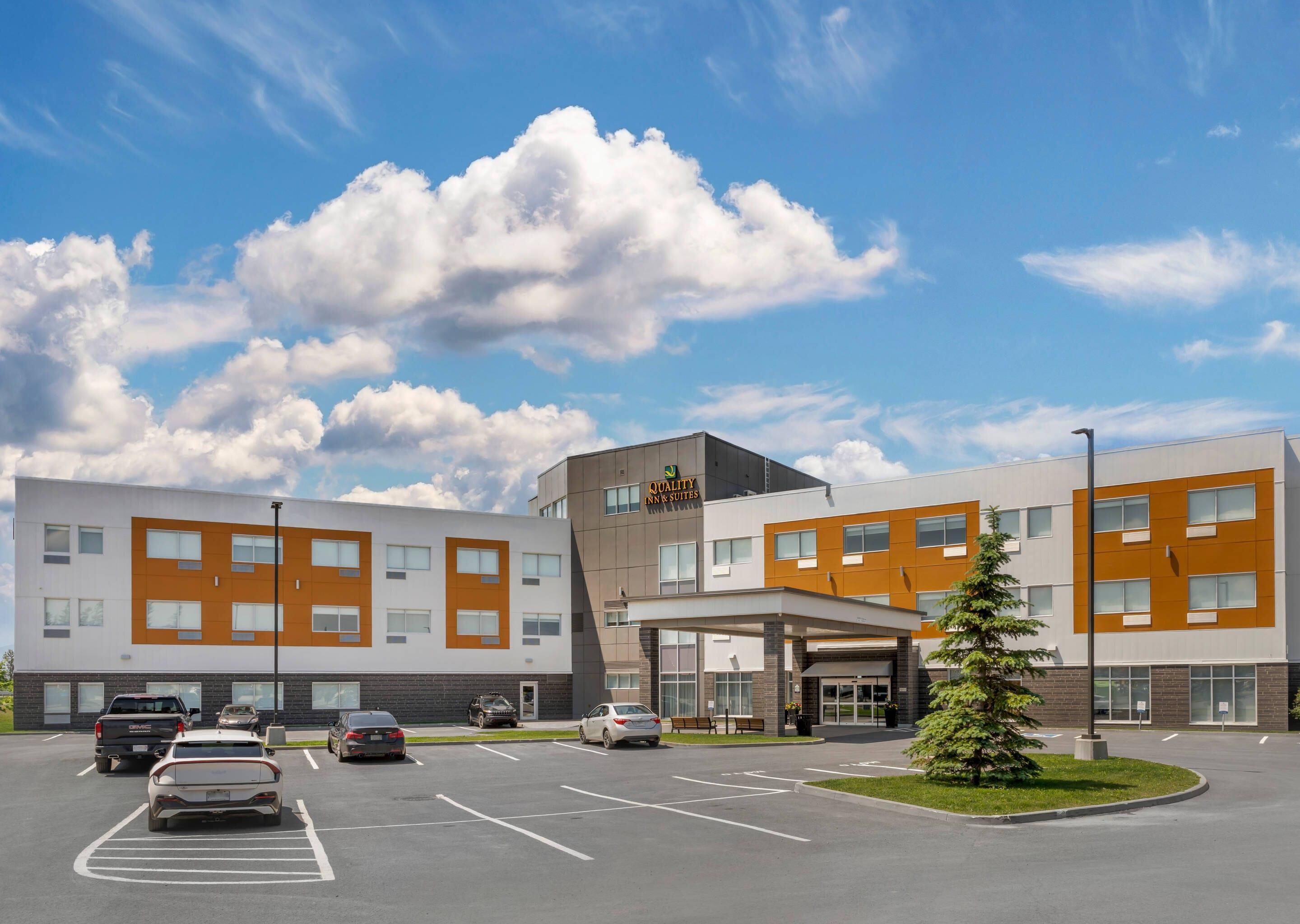 A modern hotel with a parking lot and a clear sky.