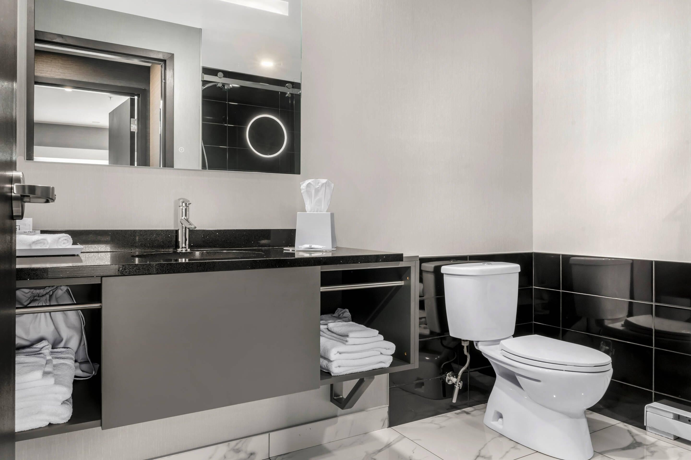 A modern bathroom with a black sink, white toilet, and a mirror above the sink.