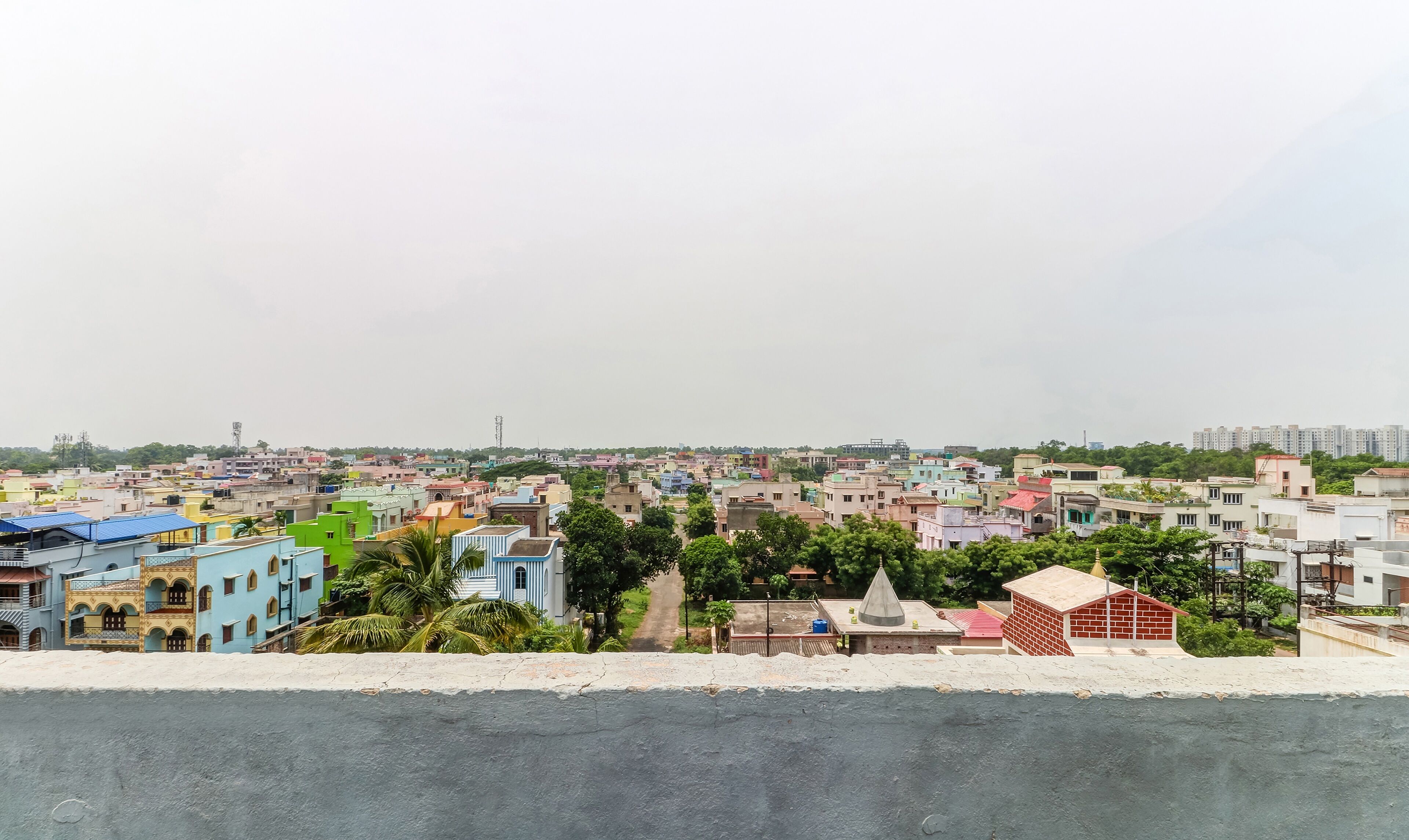 A cityscape with a variety of colorful buildings, a clear sky, and a distant view of high-rise apartments.