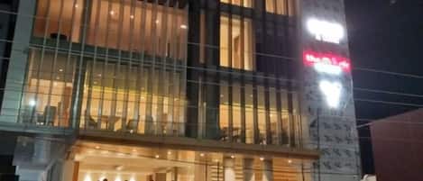 A hotel with a modern facade, large windows, and a visible entrance with people outside.