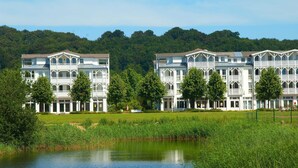 A row of white buildings with multiple stories and balconies, situated next to a body of water and surrounded by greenery. - Sonnenhus Rügen 3 a few minutes to the beach central - Sonnenhus Rügen central (Sellin)