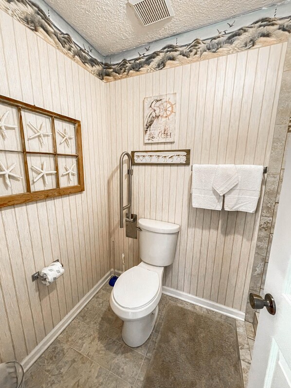 Ein Badezimmer mit Toilette, Handtuchhalter und einem Bildrahmen mit Meereslebewesen.