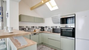 Eine moderne Küche mit hellgrünen Schränken, einer Holz Arbeitsplatte und einem eingebauten Backofen.