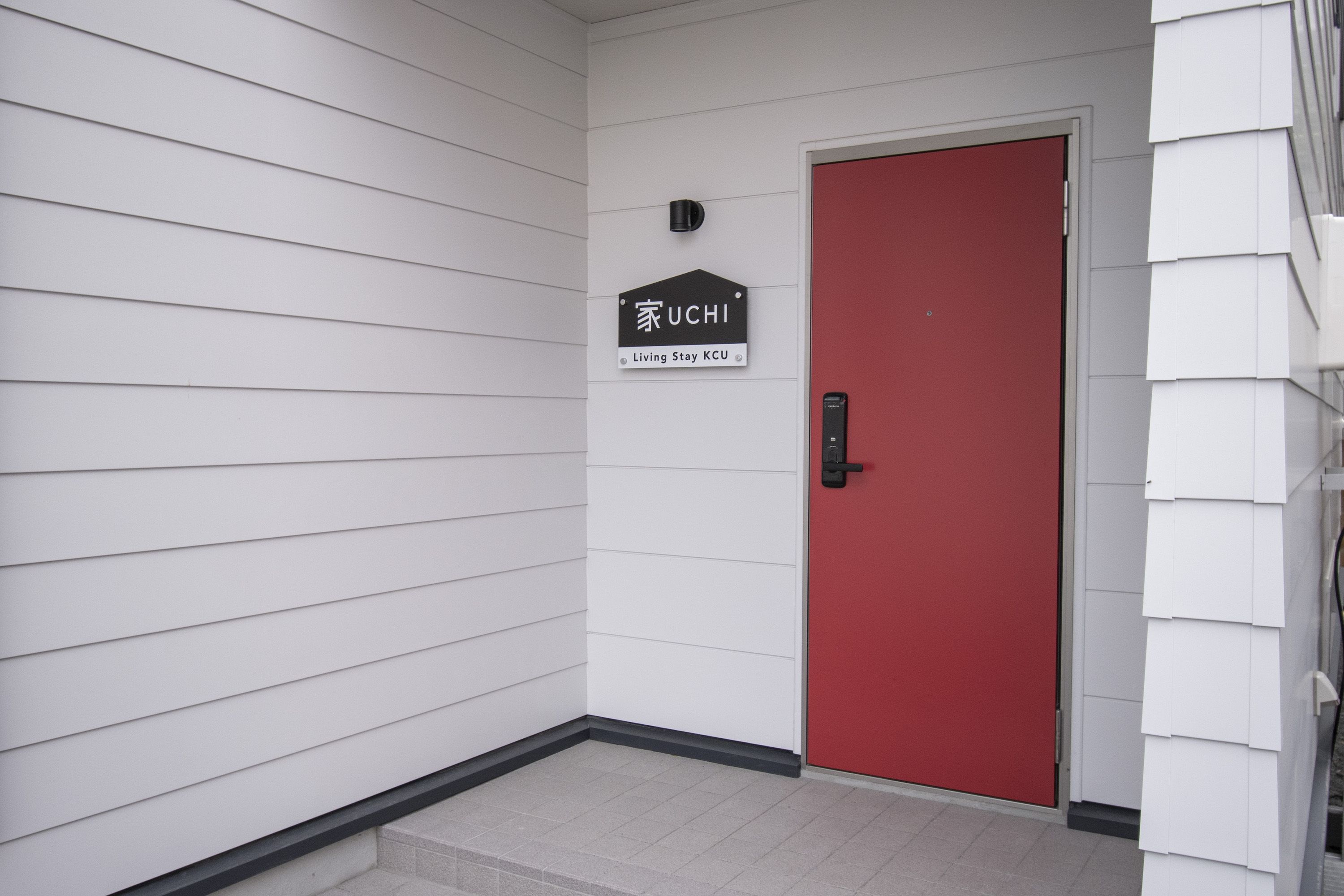 Una puerta roja con un cartel encima que dice "UCHI Living Stay KCU".