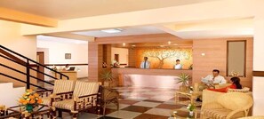 A hotel lobby with a reception desk, check-in counters, and seating areas. - Mysore Mayflower Hotel (Mysore)