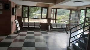 Uma área de espera com piso xadrez, um banco e uma escadaria.