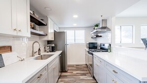 Una cocina moderna con gabinetes blancos, un refrigerador de acero inoxidable, un microondas y una estufa.