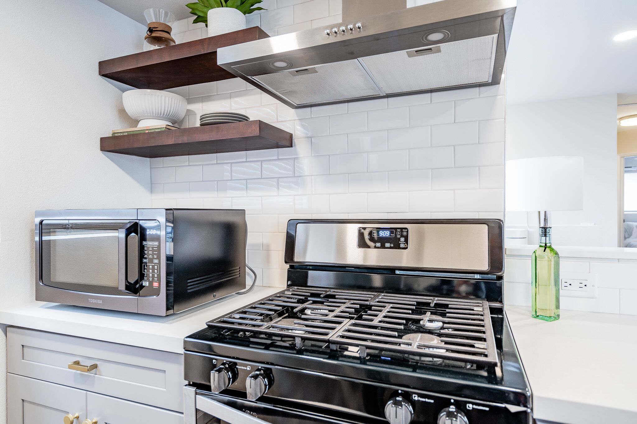 A modern kitchen with a stainless steel microwave, a gas stove, and a range hood above the stove.