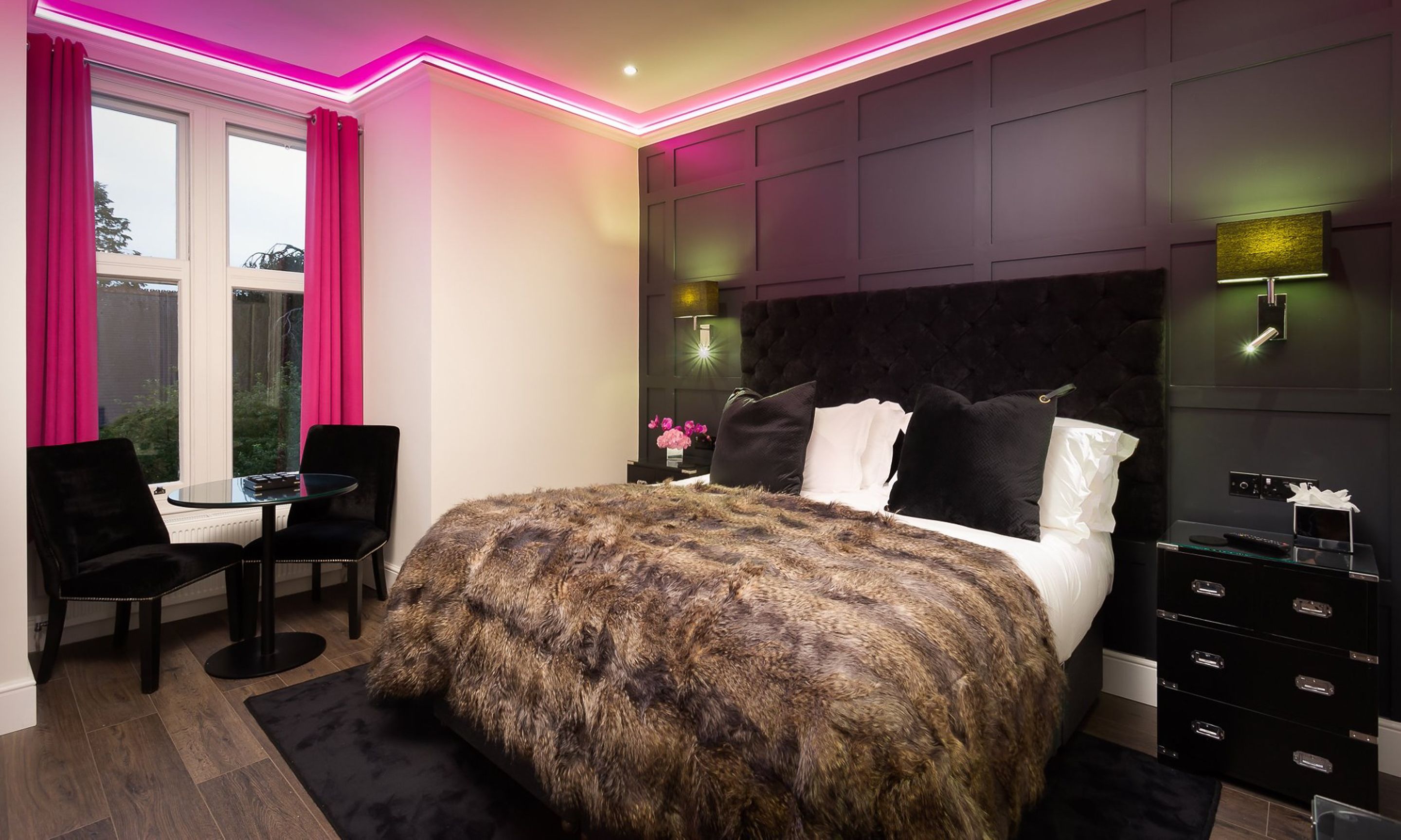A modern bedroom with a large bed, a desk, and a chair.
