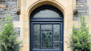 A black door with a decorative glass panel and a stone archway. - Kotel Windermere (Windermere)