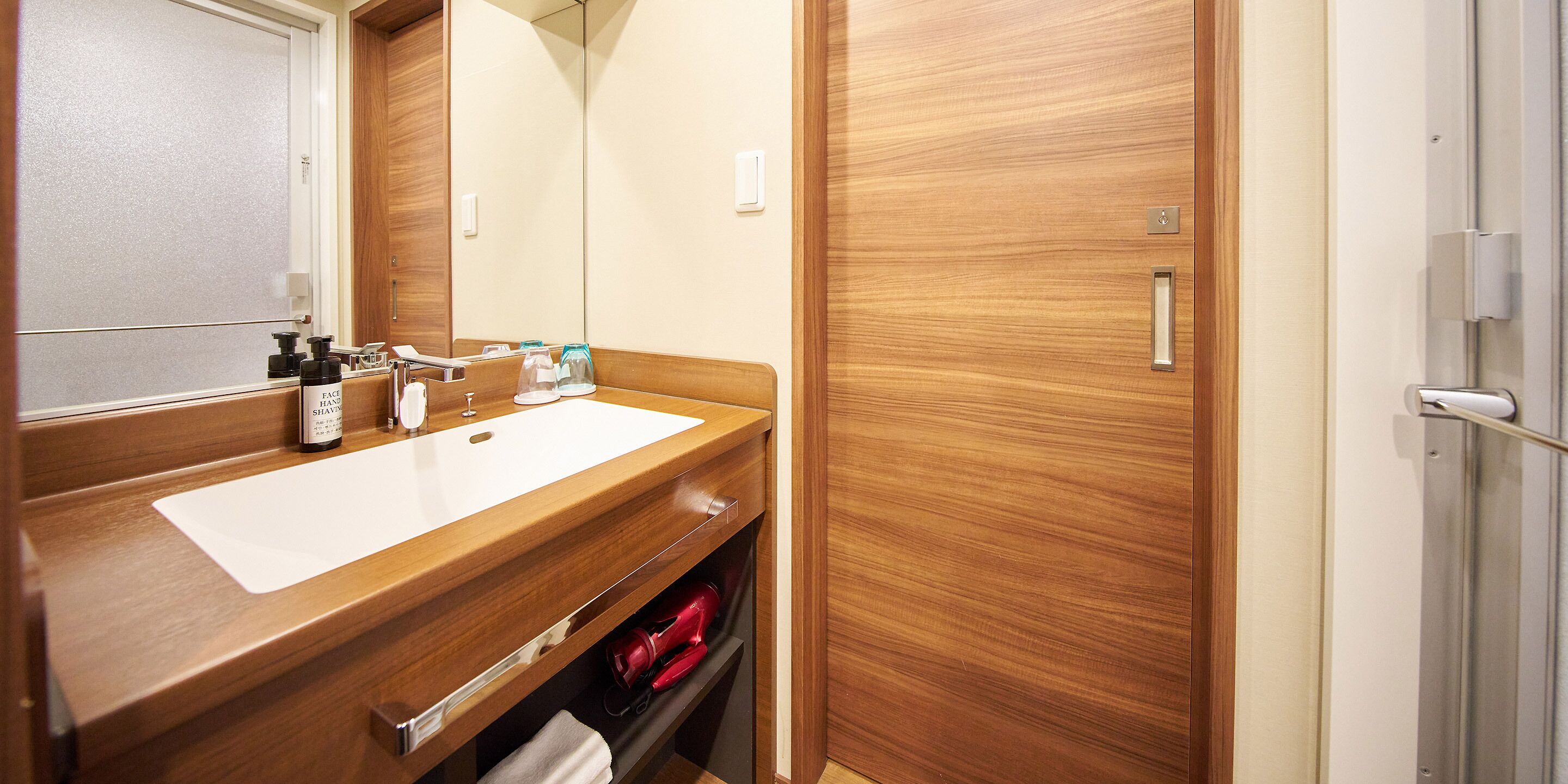 A bathroom with a wooden vanity, a mirror, a sink, and a towel rack.