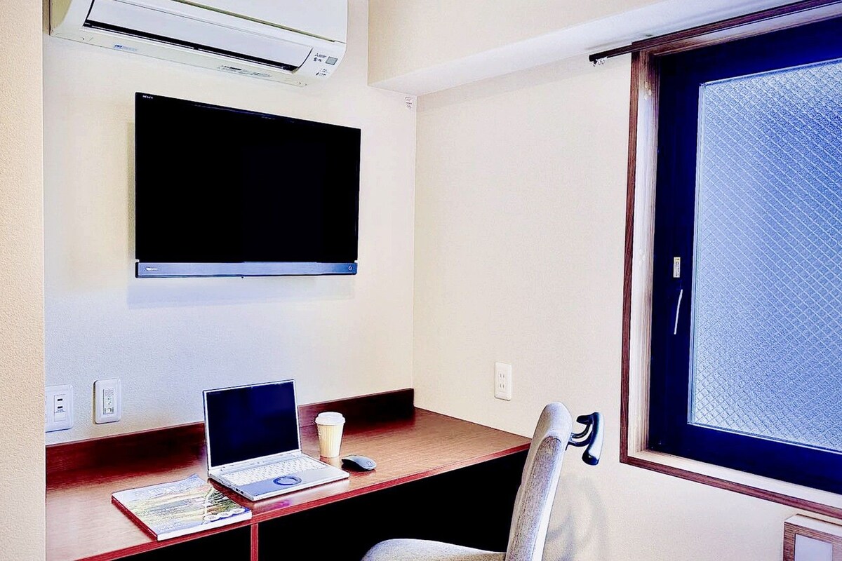 A small office space with a desk, a laptop, a cup, and a chair.