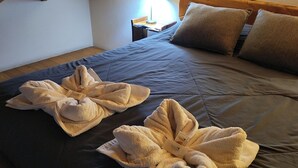 Cama bem arrumada com duas toalhas grandes e fofas dispostas em um padrão decorativo.