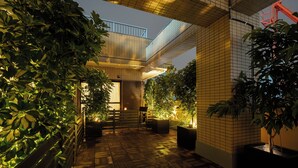 Une cour avec des murs recouverts de carreaux, un plancher en bois et des plantes en pot.