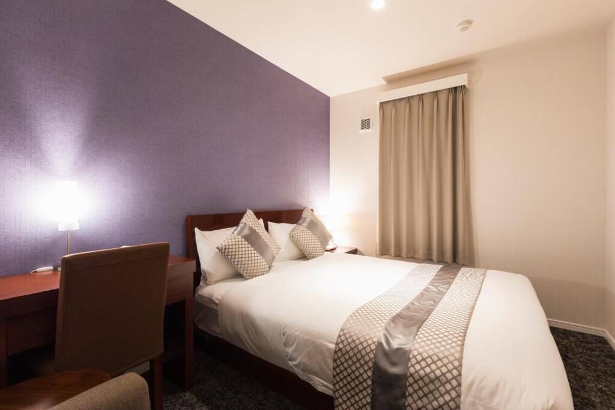 A hotel room with a bed, a desk, and a chair.