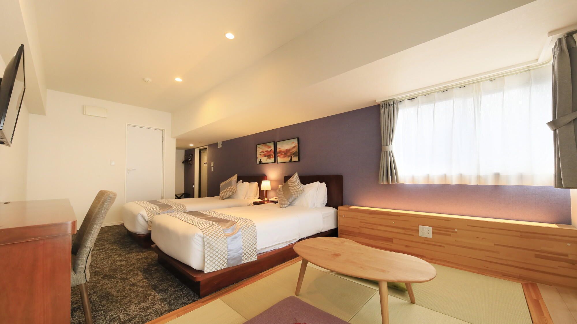 A hotel room with a bed, bedside table, chair, and a small table.