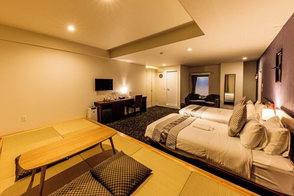 A hotel room with a bed, a desk, a chair, a television, and a mirror.