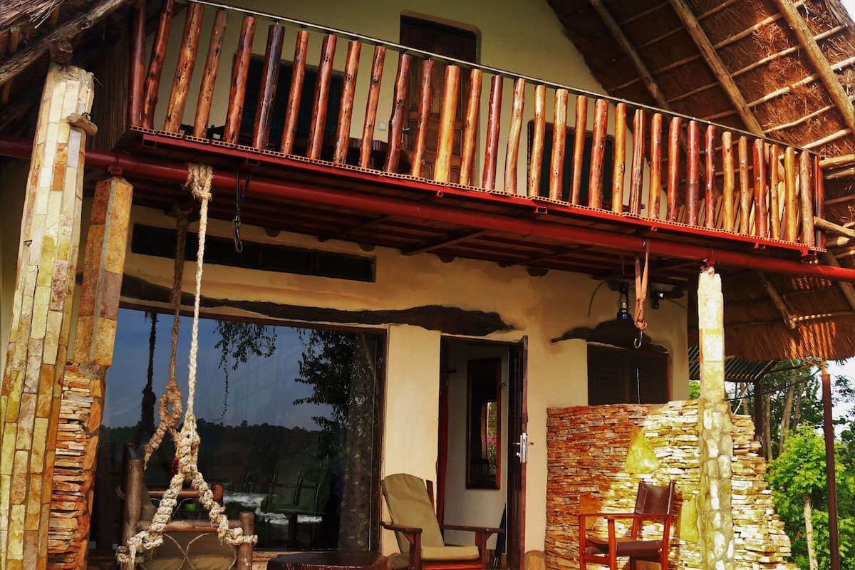 Una casa con tetto di paglia, un balcone con ringhiere in legno e un muro in pietra.