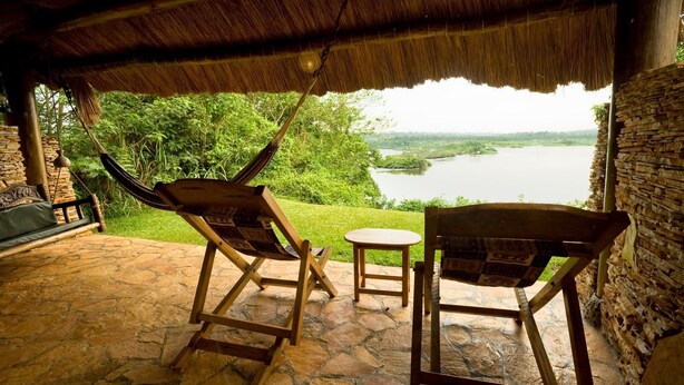 Un espacio de estar al aire libre techado con vistas a un lago y vegetación.