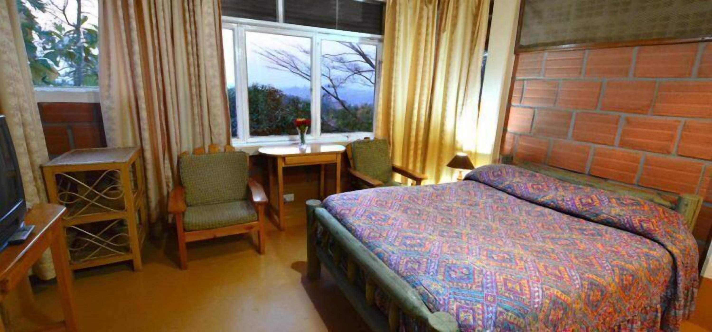 A hotel room with a bed, a desk, a chair, and a TV.