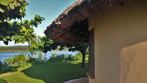 Una casa con techo de paja, un camino de ladrillo y vistas a un lago.