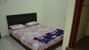 Una cama individual con una colcha estampada y dos almohadas, un cabecero oscuro y suelo de baldosas.
