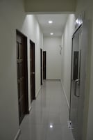 A hallway with a shiny tiled floor, doors on the left, and a glass door on the right.