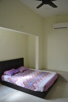 A bedroom with a bed, a ceiling fan, and an air conditioning unit.