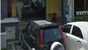 Edificio de TY Restaurant & Catering con escaparate visible y coches estacionados en la parte delantera.