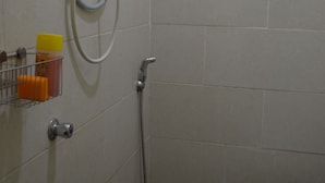 Un baño con ducha, inodoro y dispensador de jabón en la pared.