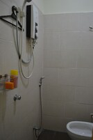 A bathroom with a shower, toilet, and a soap dispenser on the wall.