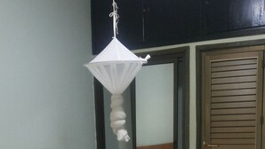 Une chambre avec deux lits, un luminaire suspendu, une porte en bois et un miroir.