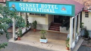 La façade de l’hôtel Sunset International, avec son panneau indicateur, ses plantes en pot et un escalier menant à l’entrée.