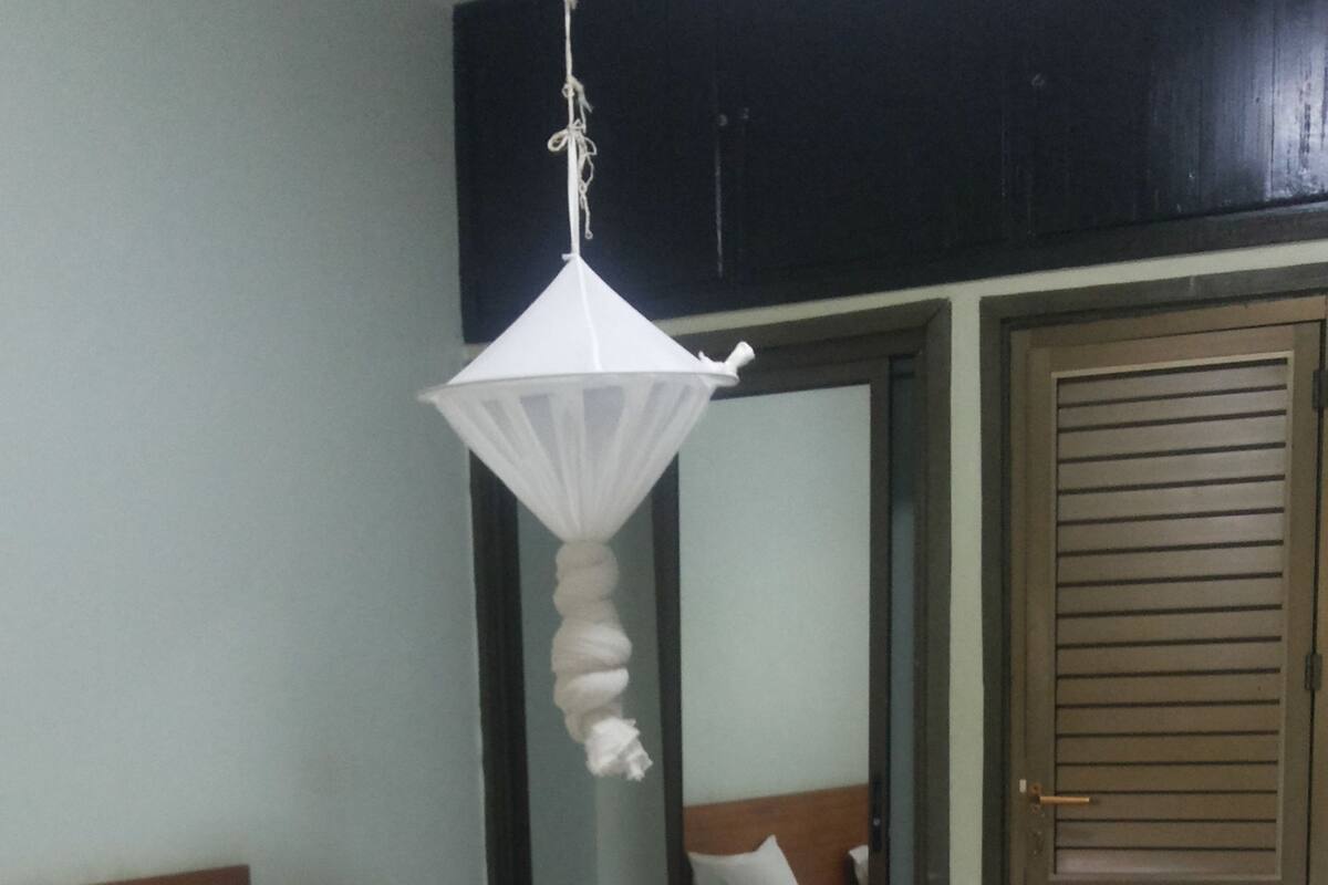 A bedroom with two beds, a hanging light fixture, a wooden door, and a mirror.