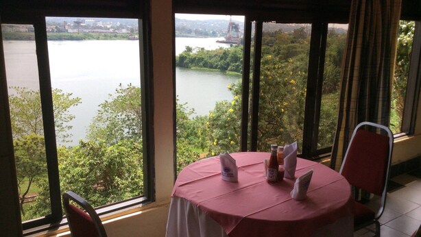 Un coin repas avec une table dressée pour deux personnes, donnant sur une rivière et une végétation luxuriante.