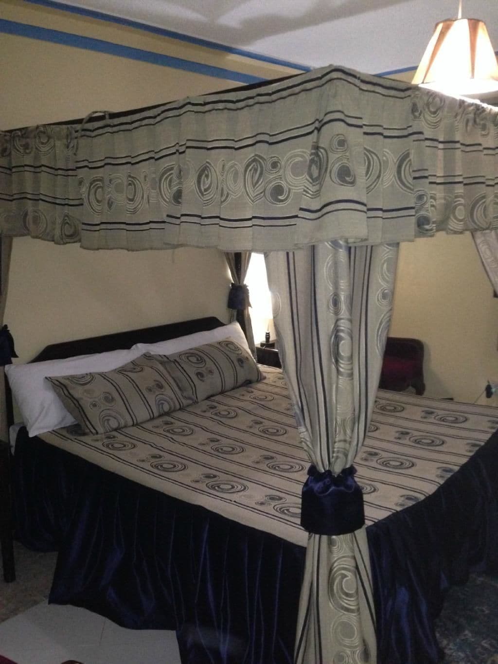 A four-poster bed with a canopy, a bedside table, and a lamp.