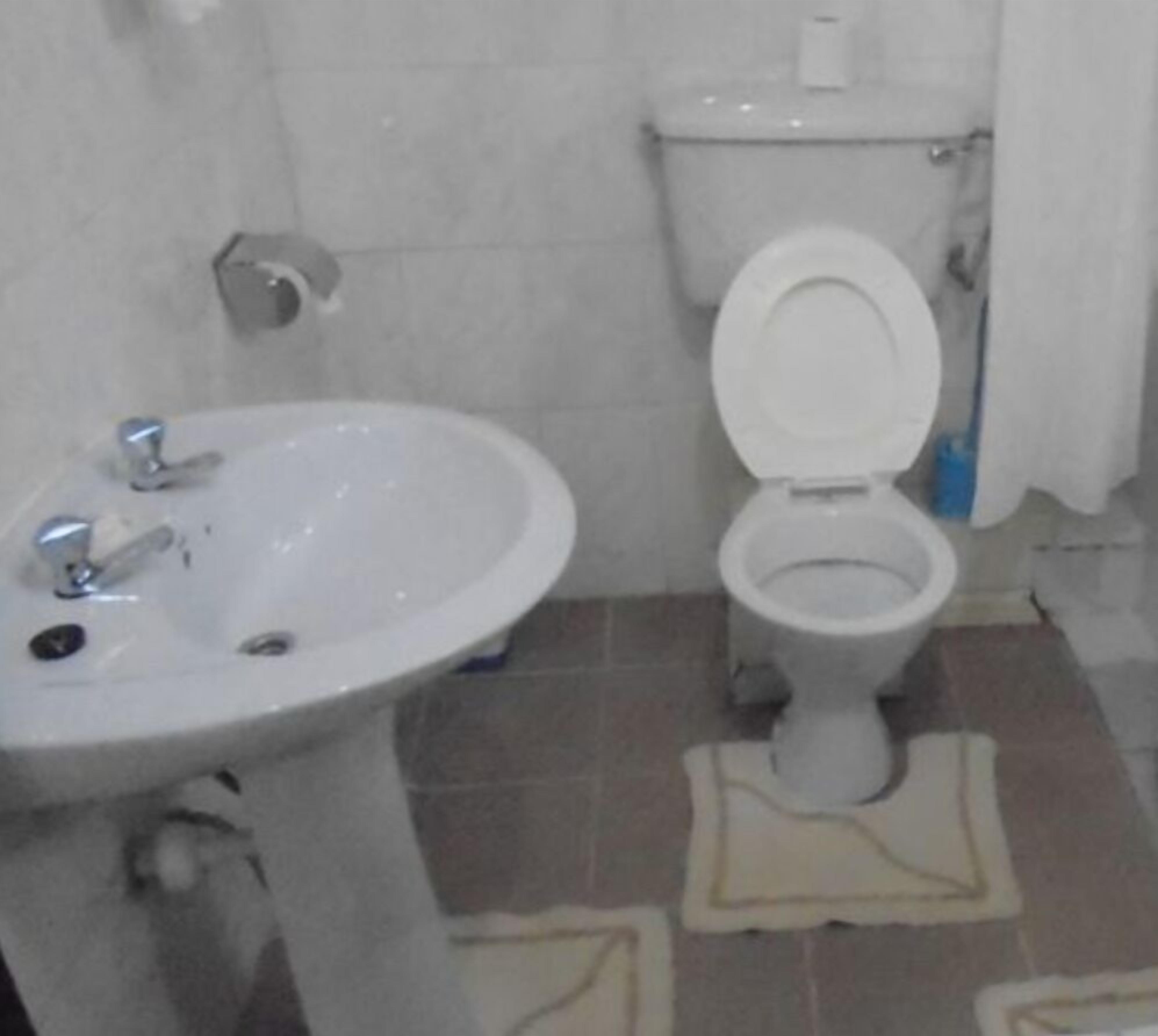 Une salle de bain avec un lavabo et des toilettes blancs.
