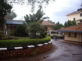 Un patio con un muro de piedra, un SUV estacionado y un edificio con un letrero que dice "Sunset Hotel International".