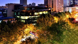 A high-rise building with multiple floors, surrounded by trees and other buildings. - Hangzhou Wenhua Jinglan Grand Hotel (Hangzhou)