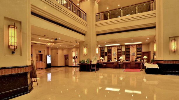 A spacious lobby with a high ceiling, a central reception desk, and a staircase connecting multiple floors. - Hangzhou Wenhua Jinglan Grand Hotel (Hangzhou)