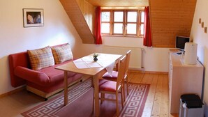 Una habitación acogedora con un sofá rojo, una mesa de madera y un televisor.