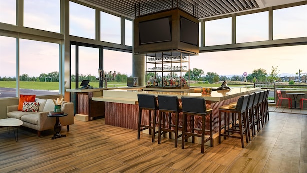 A spacious bar area with a high ceiling, large windows, and a view of the outdoors. - Hyatt Place Peña Station/Denver Airport (Denver)