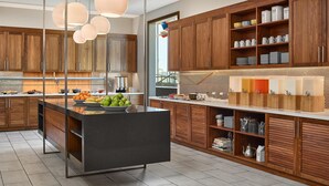 A modern kitchen with wooden cabinets, a central island, and pendant lighting. - Hyatt Place Peña Station/Denver Airport (Denver)