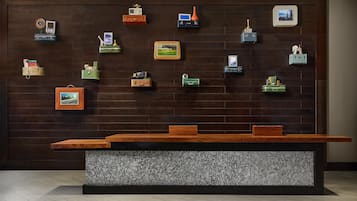 A reception desk with a wooden top and a marble base, surrounded by wall-mounted storage units with various items.