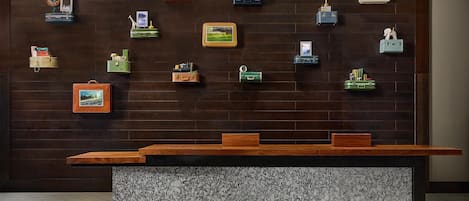 Un comptoir d’accueil doté d’un plateau en bois et d’un socle en marbre, entouré d’éléments de rangement fixés au mur et contenant divers objets.